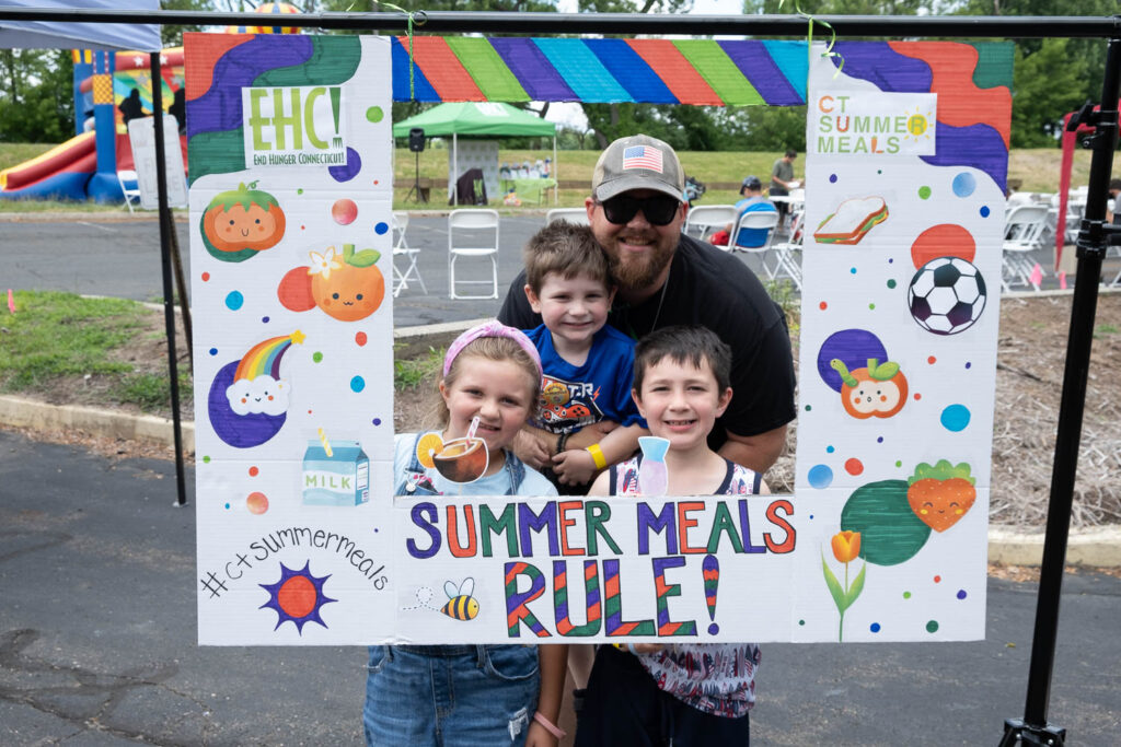 Family poses behind CT Summer Meals photobooth